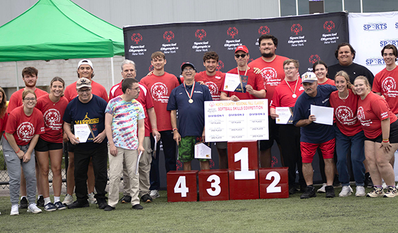 Special Olympics and SUNY Canton athletes gather around the award podium outside Roos House.