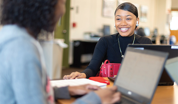 Two students study with laptops in the library.