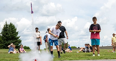 Campers launch bottle rockets on the lawn near the SUNY Canton water tower.