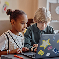 Two elementary students practice coding on a laptop.