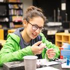 A student with green coat and glasses builds a solar hydrogen panel