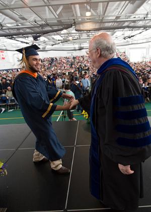 President Szafran congratulates a graduate with a handshake.