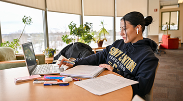 A students studies and uses a laptop in the Southworth Library.
