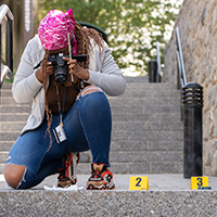 A student photographs evidence on a outdoor stairway.