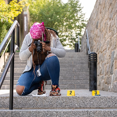 A student photographs evidence on a outdoor stairway.