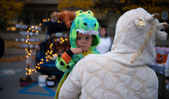 A child dressed in a dinosaur costume participates in SUNY Canton's Trunk or Treat.