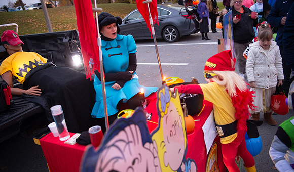 A child dressed as Hulk Hogan collects candy from a Peanuts trunk display.