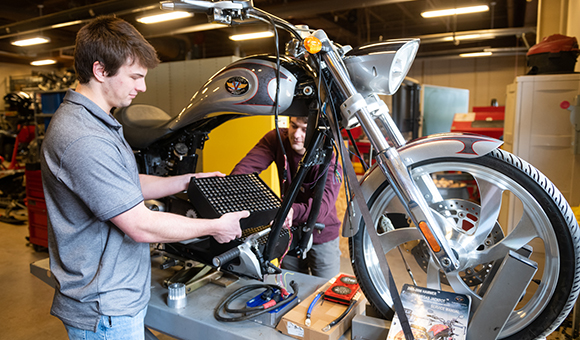 Jonathan Monnat and Conner Morse place battery cells in their electrified Victory motorcycle.