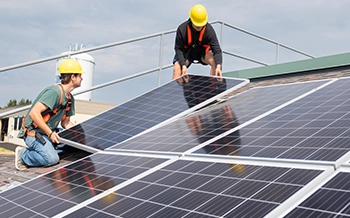 Students installing solar panels on a roof