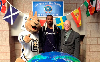 Roody, President Szafran and a student pose for a photo in front of a giant globe.