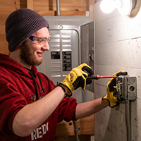 A student attaches an electrical box with a screwdriver.