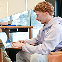 A student works on a laptop in the library.